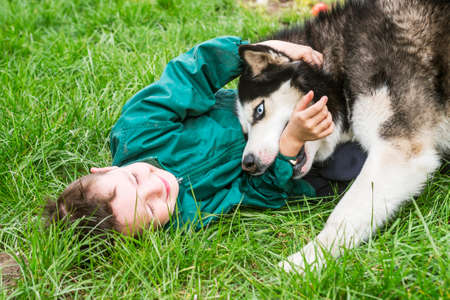 Boy playing with his dog. Happy child plays with siberian husky dog. Active children concept.の写真素材