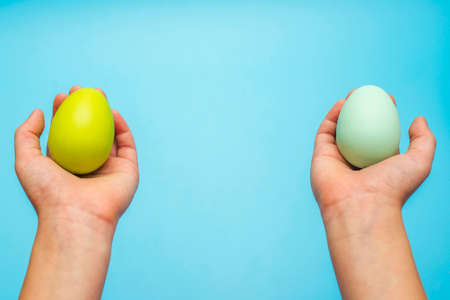 Hands holding painted easter eggs. Easter eggs in a childs hands on a blue background.の写真素材