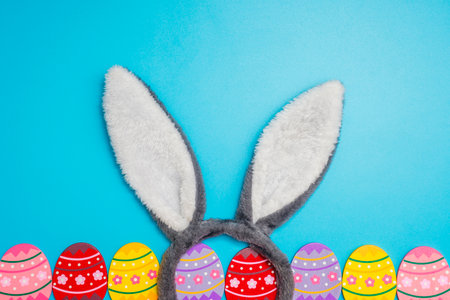 Colorful painted Easter eggs with bunny ears on blue background. Top view. Easter greeting card.の写真素材