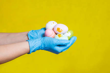 Hands in blue medical gloves holding painted easter eggs. Easter time in quarantine concept. Concept of Easter holyday during epidemy of coronavirus.の写真素材