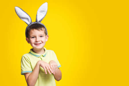 Portrait of a smiling adorable little boy wearing bunny ears on a yellow background.の写真素材