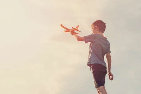 Little boy launches a toy plane into the air. Child launches a toy plane.