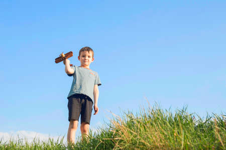 Little boy plays with a toy wooden plane. Child holds a toy wooden plane.の写真素材