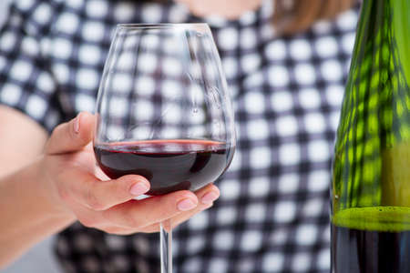 Woman holding a glass with red wine. Woman drinking alcohol.の写真素材