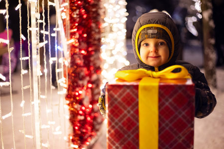 Happy child in a red Santa Claus hat with wrapped Christmas giftの写真素材