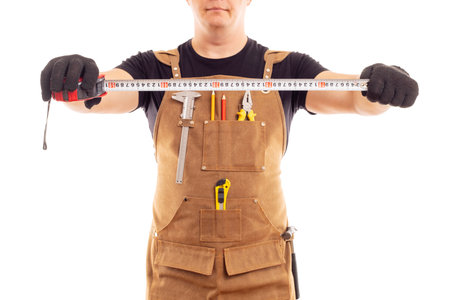 Carpenter in workers apron is holding measuring tape on white backgroundの写真素材