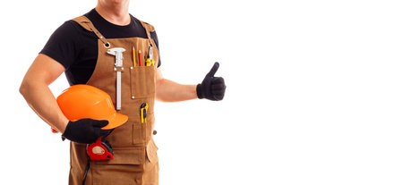 Contractor worker or carpenter in apron with tools and helmet holding thumbs upの写真素材