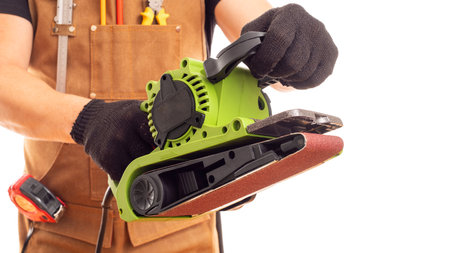 Carpenter in workers apron holding belt electric sander on white backgroundの写真素材
