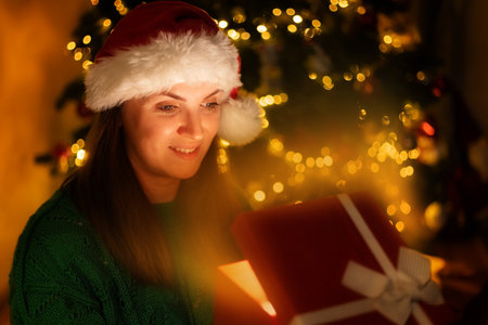Happy beautiful woman in front of Christmas tree opening gift box