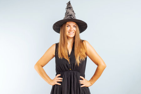 Happy brunette woman in halloween witch costume with black hatの写真素材
