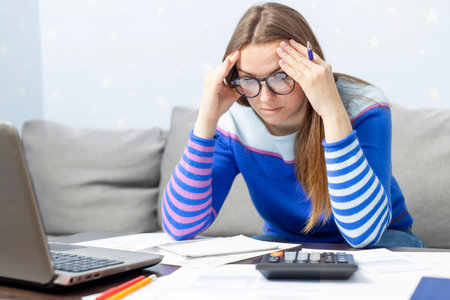 Woman using calculator for calculate domestic bills at homeの写真素材