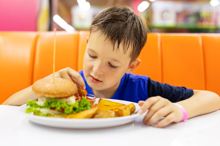 Child eating hamburger and French fries in a fast food restaurantの写真素材
