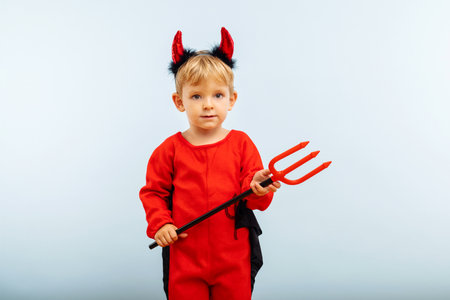 Cute little boy in devil halloween costume with horns and trident