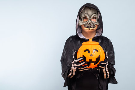 Cute little boy in a costume with a pumpkin basket jack-o-lanternの写真素材
