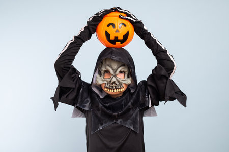 Cute little boy in a costume with a pumpkin basket jack-o-lanternの写真素材