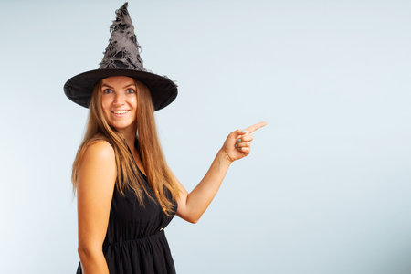 Woman in witch costume pointing with finger at copyspace sideの写真素材