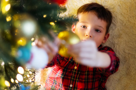 Little cute child decorating the Christmas tree on Christmas Eve at homeの写真素材