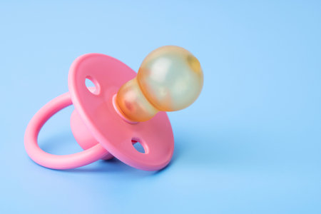 Orthodontic pacifier on a blue background. Pink baby pacifierの写真素材