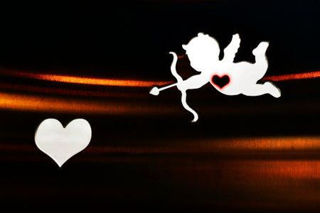 Silhouette of a cupid and a heart on the dark background