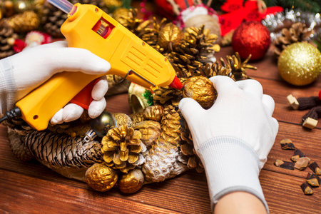 Female hands in white gloves with a glue gun make Christmas decorationsの写真素材