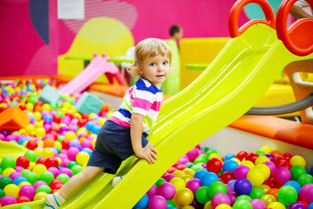 Little boy riding on slide at indoor play centerの写真素材