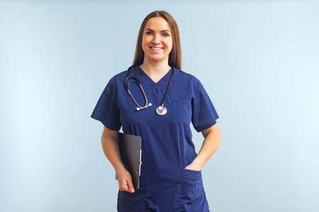 Female nurse or doctor with clipboard against a blue backgroundの写真素材