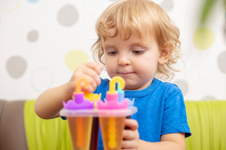 Child making ice cream from fruit juice on table at homeの写真素材