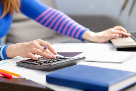Woman using calculator for calculate domestic bills for paying taxesの写真素材