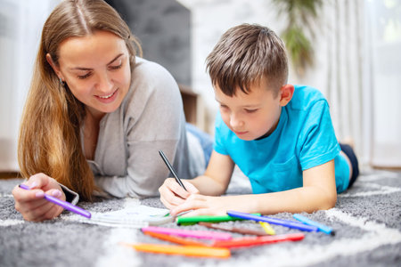 Happy family playing together on floor. Mother and son painting togetherの写真素材