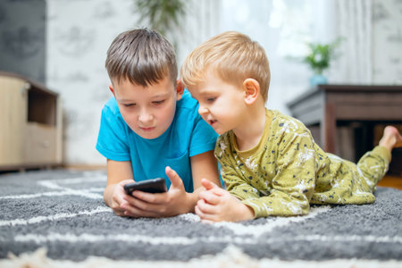 Two children watching smart phone, happy kids using smartphones togetherの写真素材