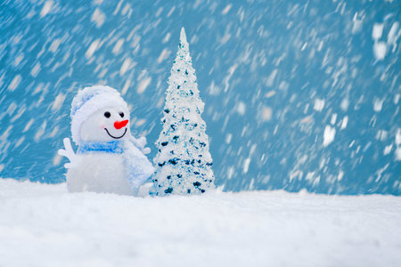 Happy snowman with Christmas tree in winter scenery with copy space