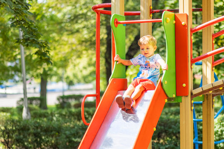 A boy having fun while playing on the playground in the daytime in summerの写真素材