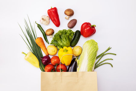 Fresh vegetables in eco friendly paper bag on white background, top viewの写真素材
