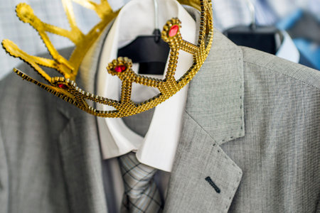Business suit with a gold crown hanging on a hangerの写真素材