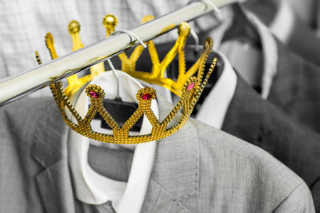Business suit with a gold crown hanging on a hangerの写真素材