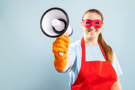 Woman in red mask, gloves and apron with megaphone on blue backgroundの写真素材
