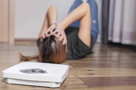 Scales and depressed young woman lying on the floor