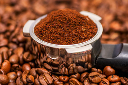 Freshly ground coffee in a metal filter on background coffee beansの写真素材