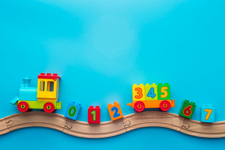 Colorful toy train locomotive with numbers on wooden railway on blue backgroundの写真素材