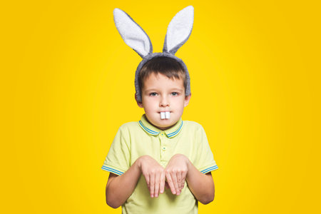 Little boy is acting as a little easter bunny on yellow background