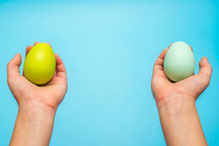 Easter eggs in childs hands on blue backgroundの写真素材