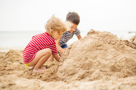 Two little boys playing on sandy beach. Cute kids building sandcastles on beachの写真素材