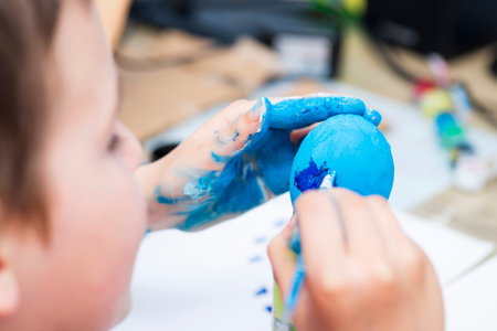 A boy painting Easter eggs at home. A child preparing the easter eggs for Easterの写真素材
