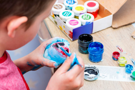 A boy painting Easter eggs at home. A child preparing the easter eggs for Easterの写真素材