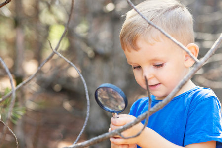 Curious boy is exploring nature with magnifying glass outdoorsの写真素材
