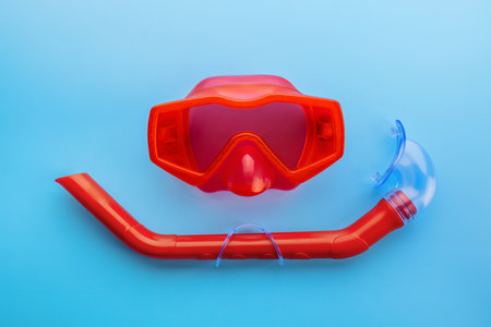 A set of red swimming mask and snorkel on a blue backgroundの写真素材