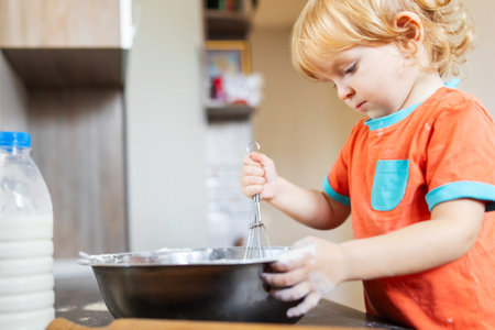 Cute little boy makes baking dough in the kitchen at homeの写真素材