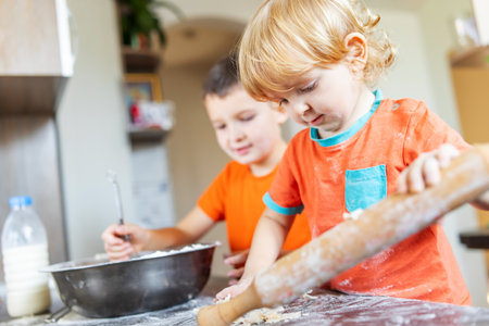 Fun family, cute kids making dough for cookies in the kitchenの写真素材