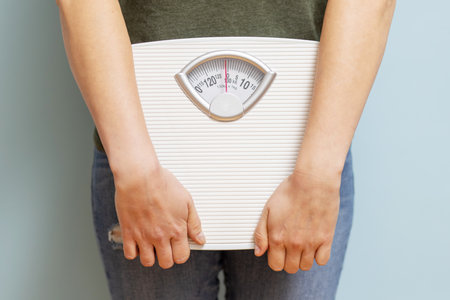 Young woman holding white scales to check the results of her dietの写真素材