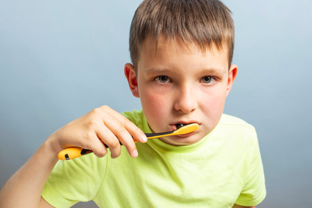 A child in t-shirt brushing teeth with toothbrush on blue backgroundの写真素材